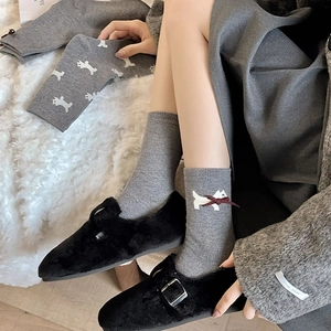 Close-up of grey cashmere socks featuring white terrier puppy pattern and red bow decoration