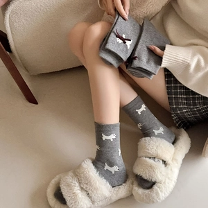 Detail of grey socks with cute dog print and red bow accent in soft knit texture