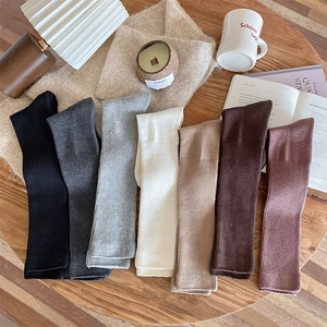 Detailed close-up of thick knitted calf socks in seven colors on a cozy wooden table