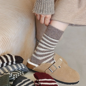 Detail of warm striped wool socks paired with cozy sheepskin-lined sandals for winter