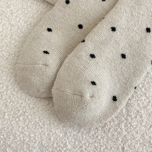 Macro shot of beige polka dot wool socks showing reinforced toe and knit texture