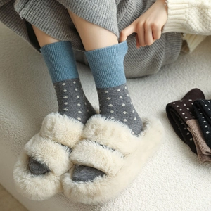 Gros plan de chaussettes en laine à pois bleus avec des pantoufles blanches douillettes