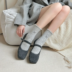 Detail of wool crew socks featuring bow embroidery and ruffled cuffs with Mary Jane shoes