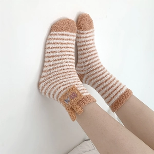 Close-up of cute 3D ear coral fleece socks with orange and white stripes for home