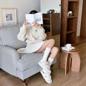 Close-up of white vertical striped calf socks paired with fuzzy slippers and pleated skirt