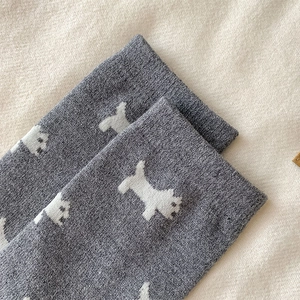 Close-up of gray knit socks featuring cute white dog pattern and warm wool texture