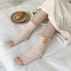 Close-up of orange striped fleece socks with cute 3D ears on a cozy white background