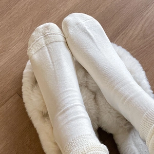 Detail view of white knitted calf socks with thick terry texture and ribbed cuffs for warmth