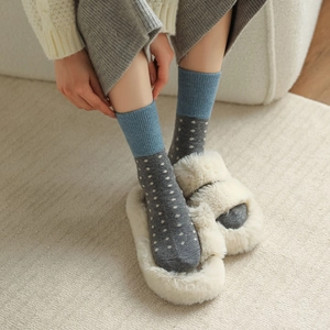 Détail de chaussettes en laine à pois avec bords bleus sur un tapis doux et chaud