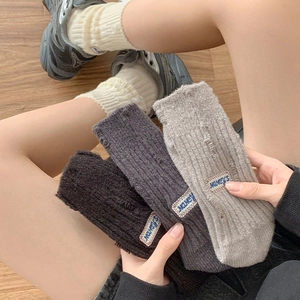 Close-up of thick knitted leg warmers with embroidery patches and distressed hole details