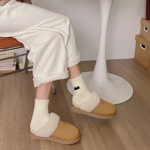 Détail de chaussons en daim camel avec doublure en peau de mouton synthétique et semelle épaisse