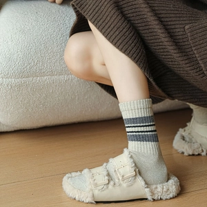 Close-up of cozy off-white faux shearling double-buckle slippers with striped wool socks