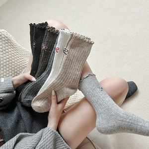 Detailed knit texture and embroidered bow on warm wool socks with ruffled edges