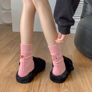 Close-up of pink embroidered socks with Follow Your Heart text and red heart detail