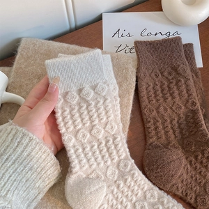 Detail of thick wool socks showing 3D diamond texture and ribbed cuffs in earthy tones