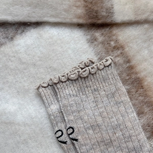 Detailed close-up of wool socks featuring ruffled cuffs and delicate black embroidery