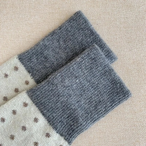 Gros plan sur la maille des chaussettes en laine à pois gris et beige avec finitions