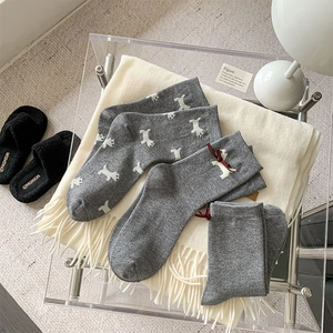 Close-up of gray knit socks featuring cute puppy embroidery and red ribbon details