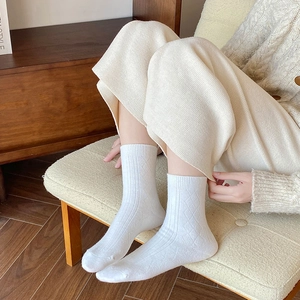 Detail of white knee-high socks featuring argyle patterns and ribbed texture on fabric