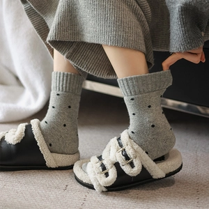 Close-up of thick grey wool socks with black polka dots and warm knit texture