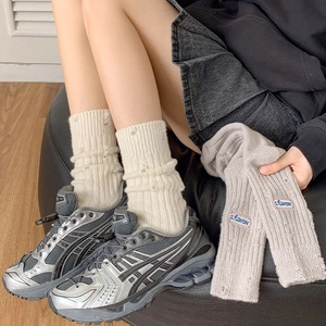 Detail of distressed knit mid-calf socks featuring letter embroidery and ripped design