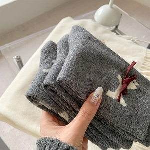 Detail showing grey cashmere socks with white puppy patterns and a red 3D ribbon bow
