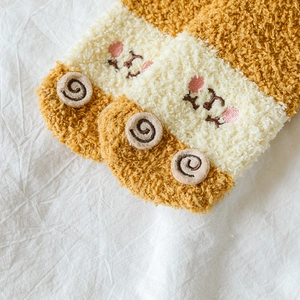 Close-up of thick striped coral fleece socks with cute embroidery and fluffy texture