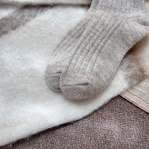 Detailed texture of thick knit wool socks with ribbing on cozy cream fleece background