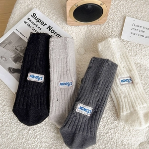 Detail of four pairs of ribbed knit socks with embroidery tags and distressed holes