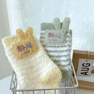 Detail of coral fleece thick striped socks with cute 3D ears in a storage basket