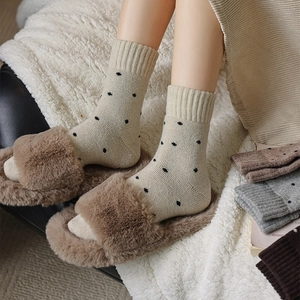 Detailed view of warm polka dot wool socks paired with plush slippers in home setting