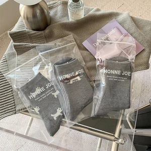 Three pairs of grey puppy pattern socks in individual premium zipper bag packaging