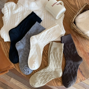 Detailed knit texture of five thick wool socks in beige brown grey black and white tones