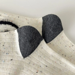 Macro detail of knit texture and gray reinforced heel on Japanese confetti socks
