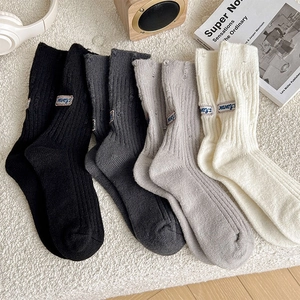 Close-up of distressed knit socks in neutral tones with vintage brand label on plush fabric