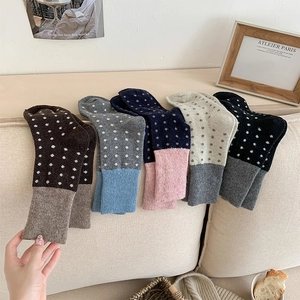 Détail de cinq paires de chaussettes en laine à pois vintage sur un canapé beige