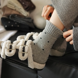 Close-up of grey polka dot wool socks with ribbed cuffs worn for winter warmth
