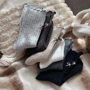 Detail of wool blend socks featuring ruffle cuffs and delicate bow embroidery accents
