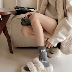 Detail of grey knitted socks with white puppy pattern and plush faux fur cross-band slippers
