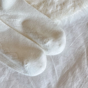 Detailed close-up of white cashmere knit sock with elegant diamond pattern texture
