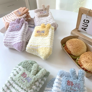 Close-up of striped coral fleece socks with cute 3D ears and soft pastel color texture