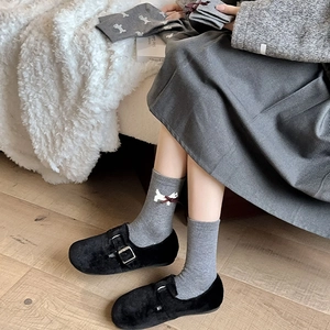 Detail of grey knitted dog socks featuring red 3D bows paired with black platform shoes
