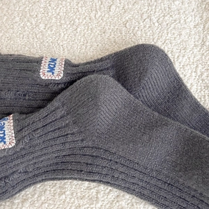 Macro detail of charcoal grey ribbed knit socks with embroidered label on thick wool fabric