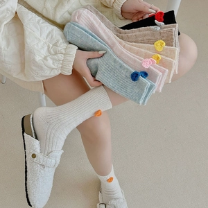 Gros plan de chaussettes en laine pastel avec breloques cœur et texture tricotée