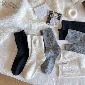 Macro detail of knit argyle cashmere socks in black, white, and grey for winter warmth