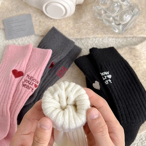 Detail showing plush cotton socks with heart embroidery and ribbed cuffs in soft tones