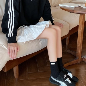 Fashionable black ribbed mid-tube socks paired with a white skirt and sneakers