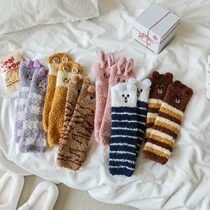Detail of coral fleece striped socks with cute 3D ears and embroidery on white fabric