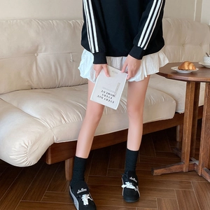 Close-up of black mid-calf socks styled with white ruffled skirt and black sneakers