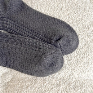 Detailed close-up of dark grey thick ribbed knit socks with warm cotton blend texture